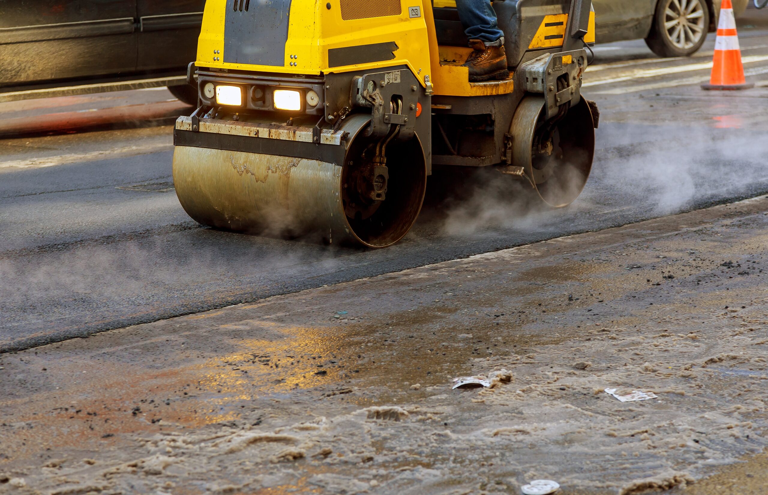 Urban road is under construction, asphalting in progress, fragment of yellow roller